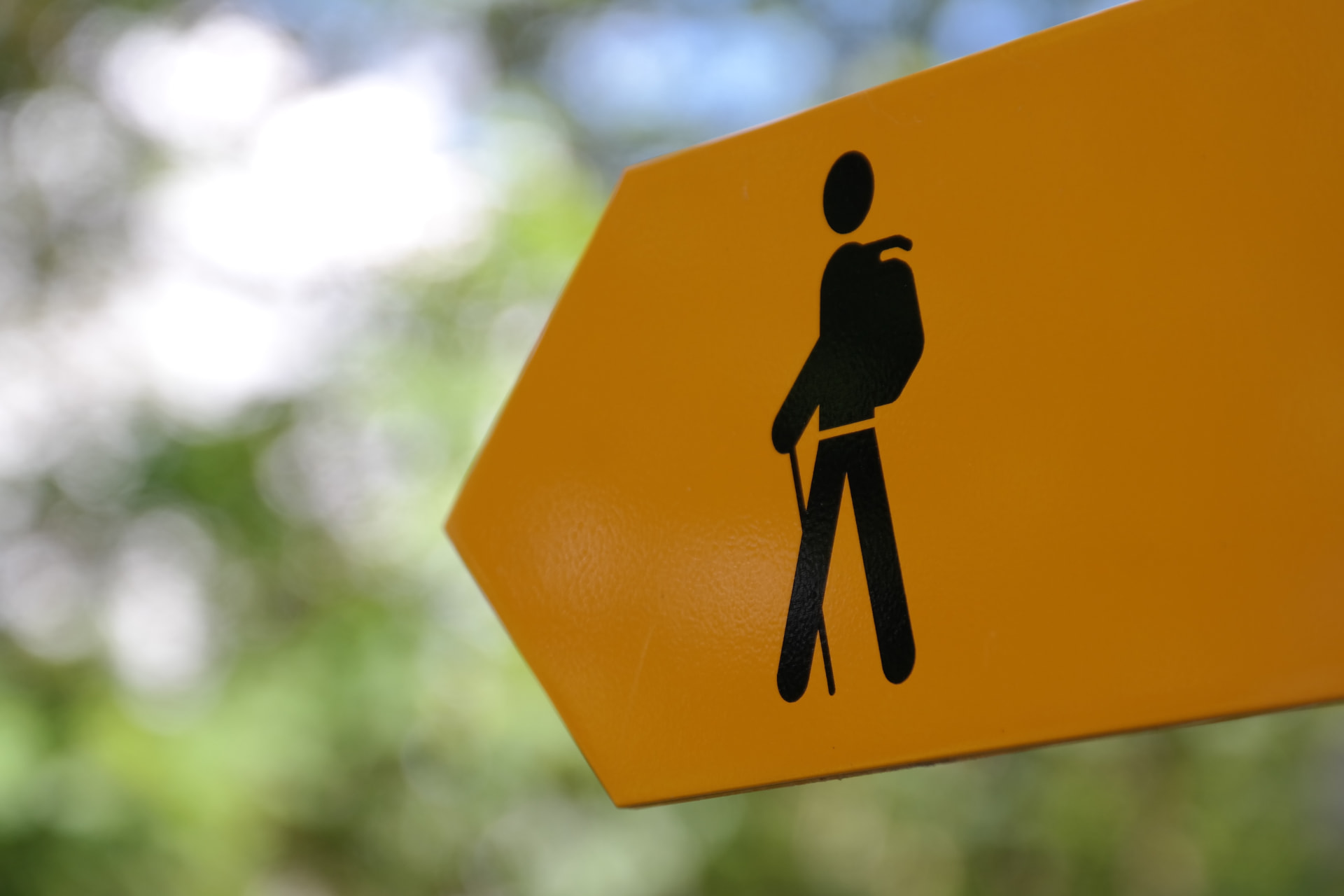 Foto eines gelben Schweizer Wanderwegweisers mit Wanderer-Symbol vor grünem Hintergrund